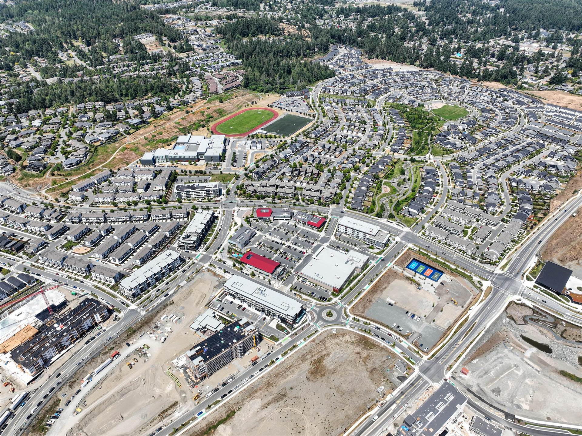 Wide aerial view of the Royal Bay community in Colwood showing the secondary school, running track and retail core