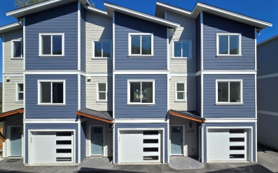 Three storey townhomes with white garage doors at Happy Valley Townhomes in Langford, built by Walking Stick Developments Inc.