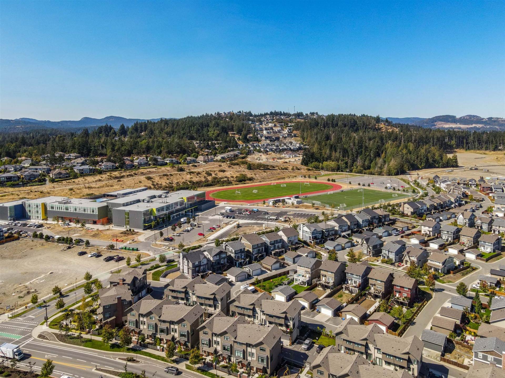 Aerial view of Royal Bay Secondary School in Colwood with its running track, turf field and surrounding homes